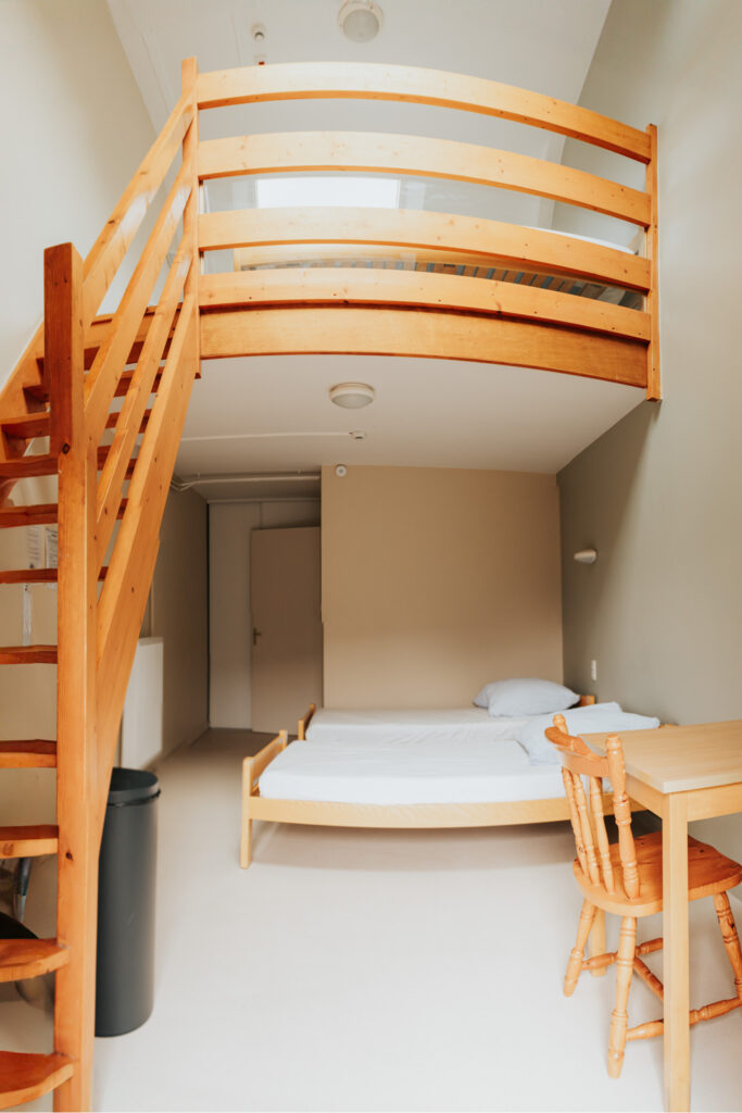 Une chambre en mezzanine avec deux lits et une table en bas