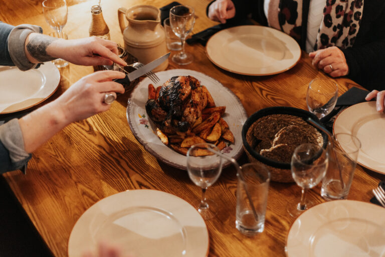 Photo d'un poulet à partager. Une personne coupe le poulet qui est au milieu de la table.