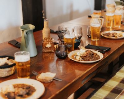 Une table avec des assiettes de viande et des pintes de bière
